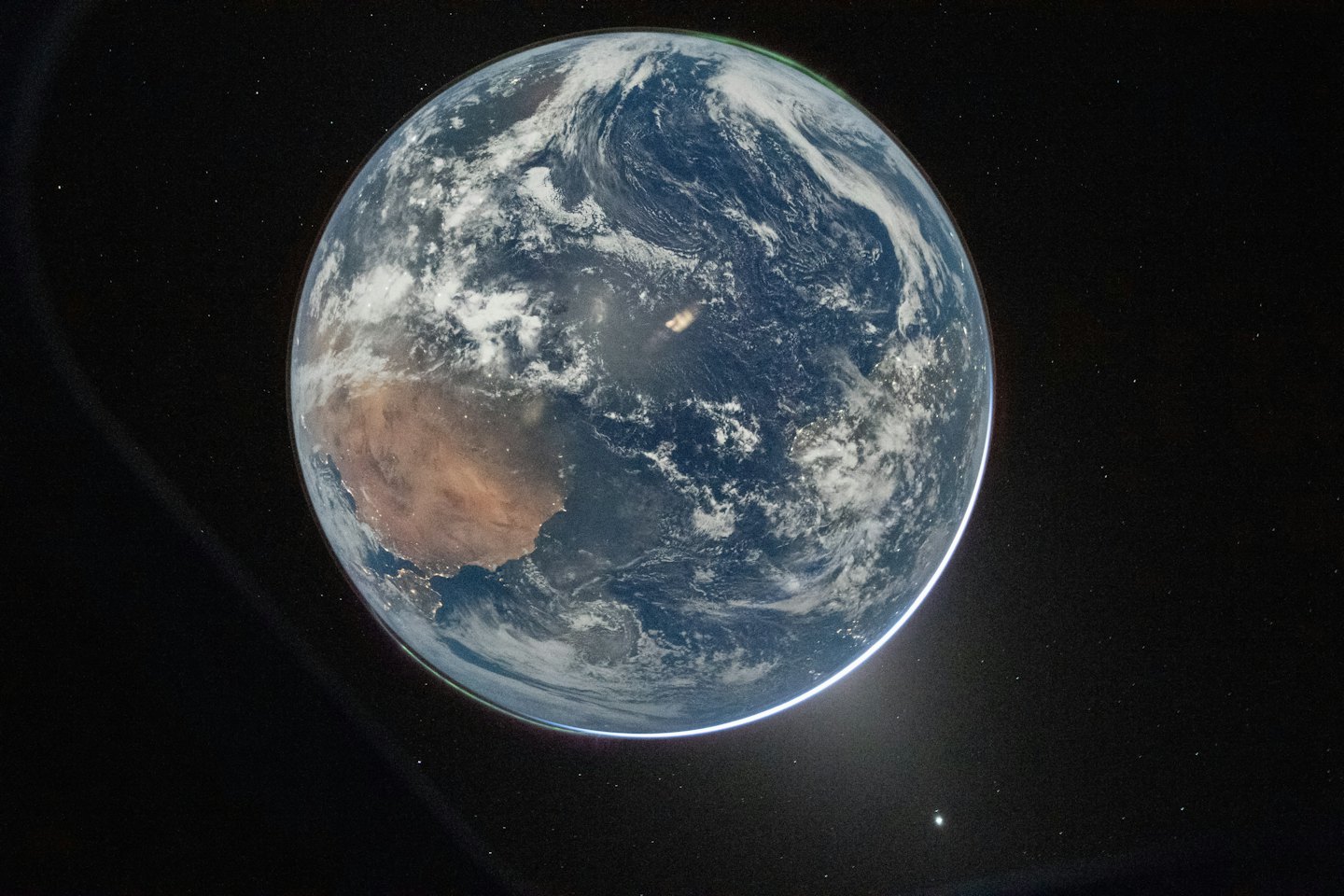 Planet Earth as seen from space with swirling clouds over land and sea.