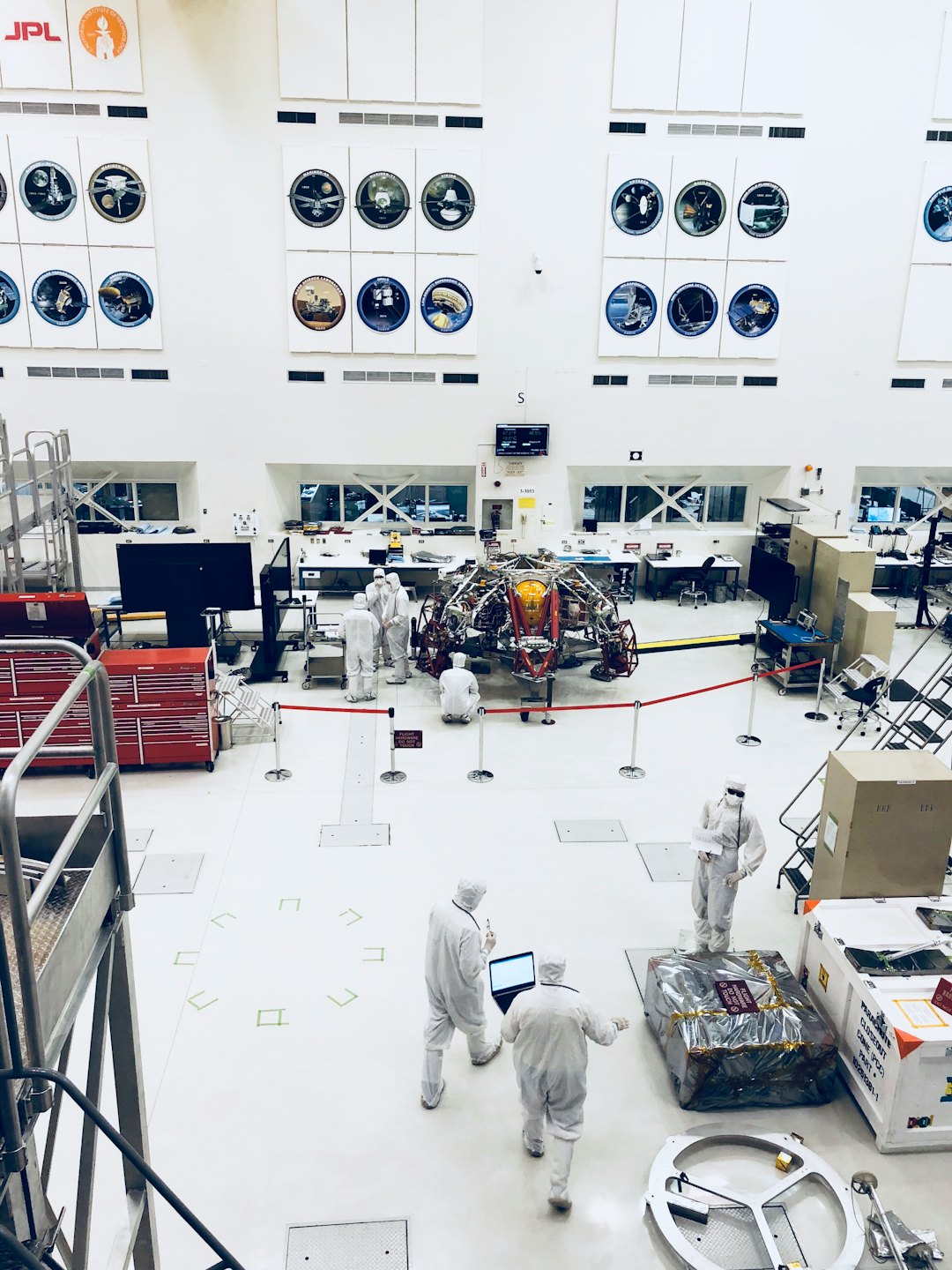 Scientists assemble a large spacecraft in a cleanroom.