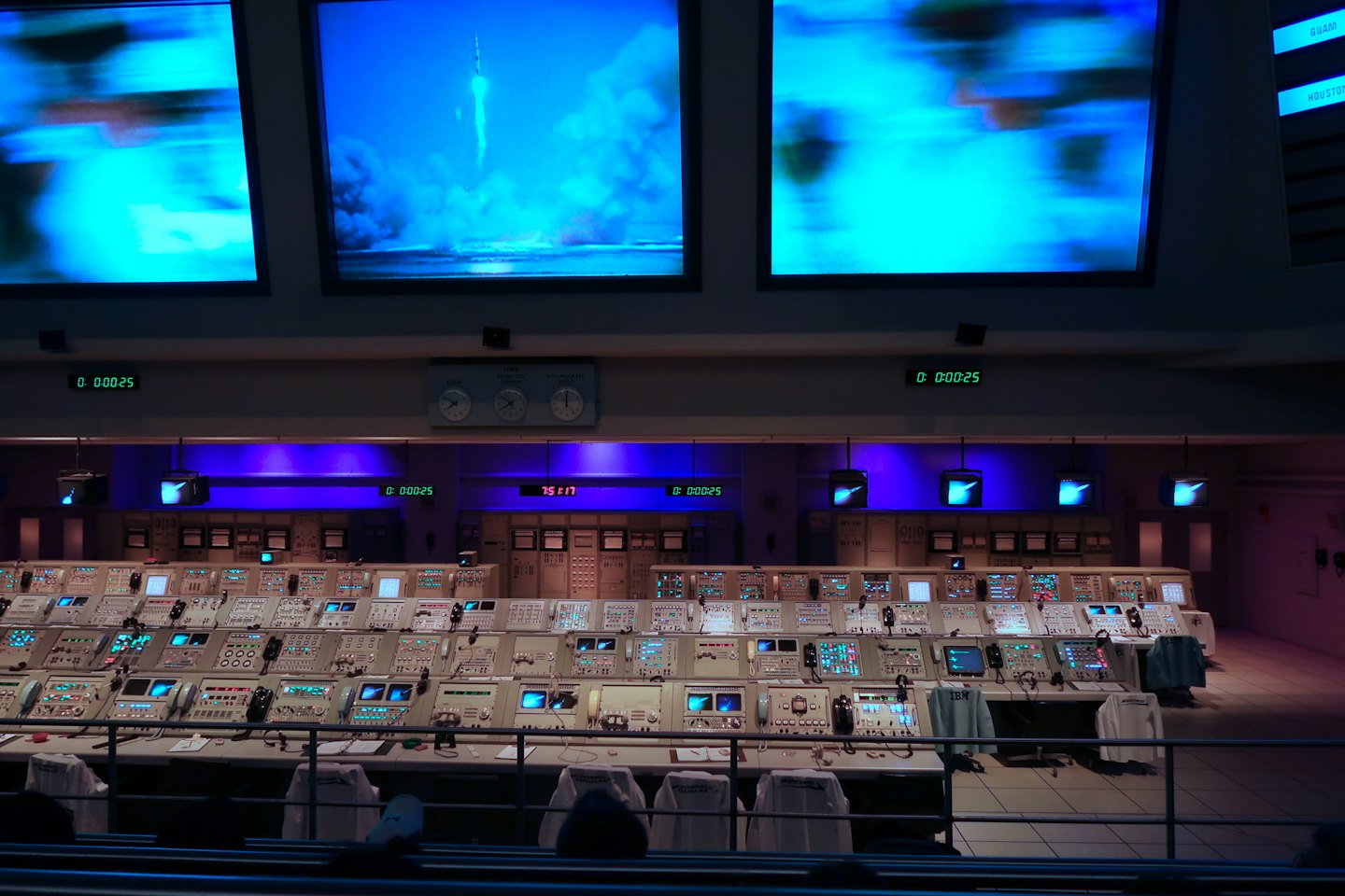 Mission control room consoles with rocket launch monitors.